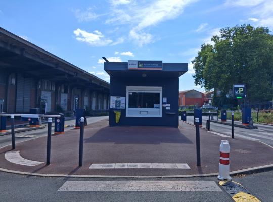 Local d'accueil EFFIA bleu sombre situé au centre des voies d'accès au parking.