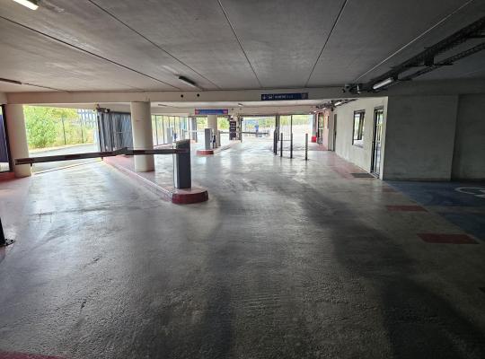 Zone de sortie couverte du parking avec barrières et panneaux de signalisation.