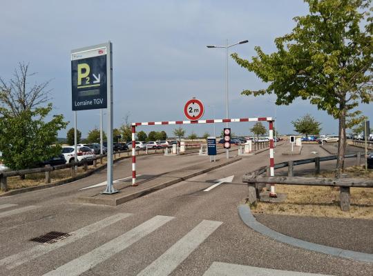 Entrée du parking P2 Lorraine TGV avec un grand panneau d'affichage, un passage piéton et un portique limitant la hauteur à 2 mètres.
