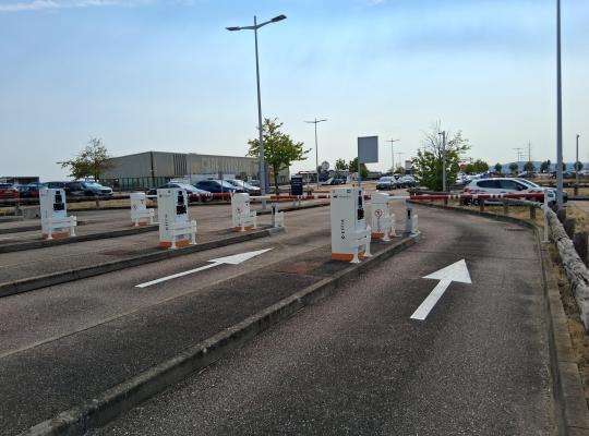 Voies de circulation marquées par des flèches au sol, menant à des barrières automatiques de péage et des bornes de ticket EFFIA.