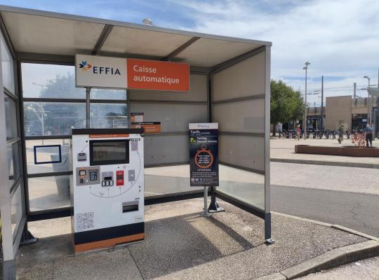 Voitures garées sur le parking extérieur devant le bâtiment de la gare.