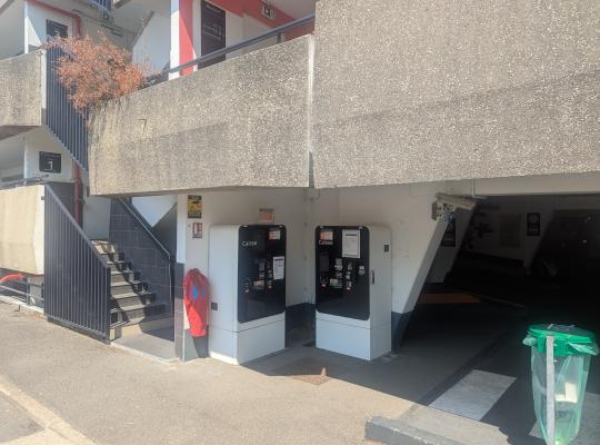 Deux caisses automatiques de paiement abritées sous la structure d'un parking.