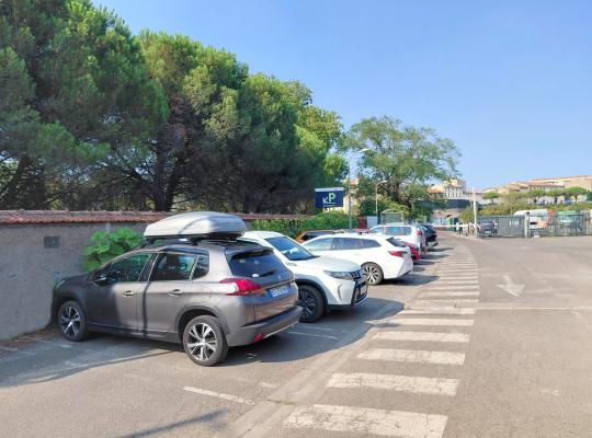 Rangee de véhicules stationnés le long du mur d'enceinte ombragé du parking.