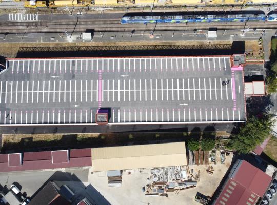 Vue aérienne du parking ouvrage EFFIA Gare de Nangis, de sa toiture aménagée et des voies ferrées à proximité.