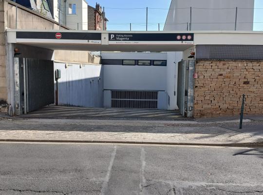 Entrée d'un parking pour abonnés Magenta, avec portail métallique ouvert.