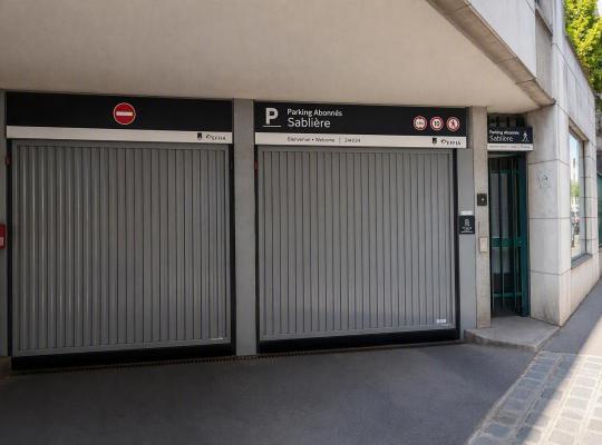 Entrée du Parking Abonnés Sablière avec portes de garage grises fermées.
