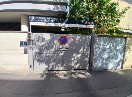 Entrée d'un parking couvert pour abonnés avec des portes de garage et des panneaux de signalisation.