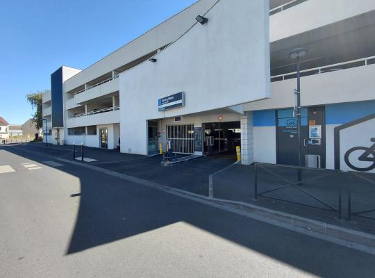 Façade du parking relais Persan-Beaumont montrant l'accès des véhicules et l'espace vélos.