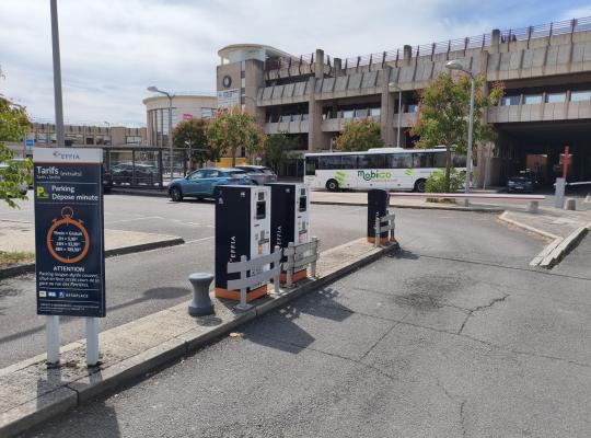 Borne de ticket et barrière d'accès à l'entrée du parking dépose-minute.