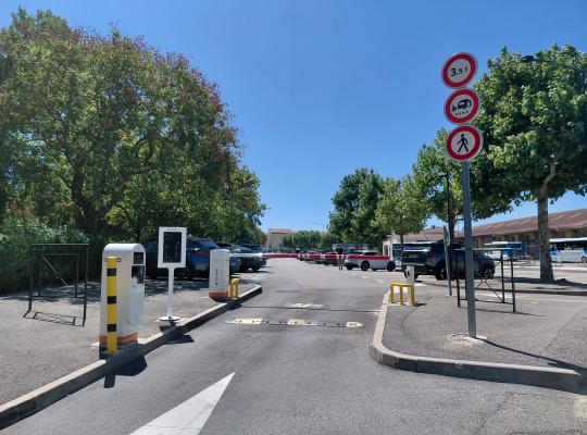 Accès au parking extérieur équipé de bornes de distribution de tickets, de barrières levantes et de la signalisation réglementaire.