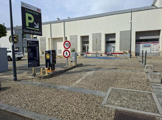 Entrée du parking courte durée avec borne de distribution de tickets et panneau d'affichage des tarifs.