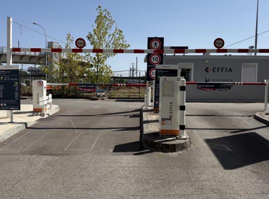 Voies d'entrée et de sortie avec bornes de contrôle, barrières automatiques et local d'accueil.
