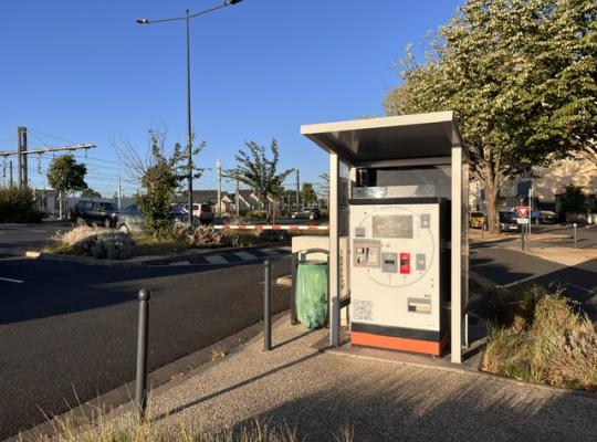 Borne de paiement automatique du parking installée sous un abri de protection vitré.