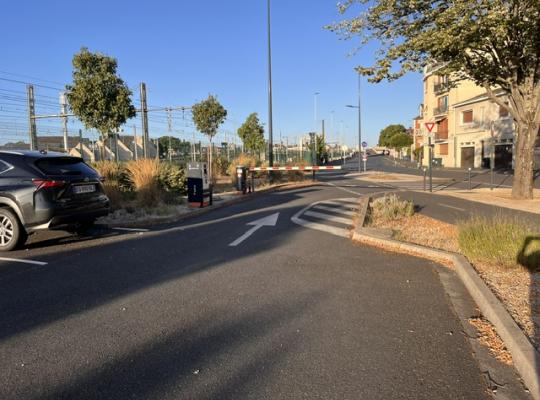 Voie de sortie du parking guidée par une flèche au sol et sécurisée par une barrière relevable.