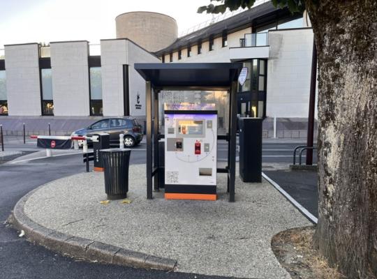 Caisse automatique de paiement sécurisée située sous un abri couvert à l'entrée du parking.