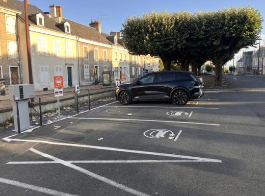 Places réservées aux véhicules électriques avec bornes de recharge de proximité et signalétique orange.