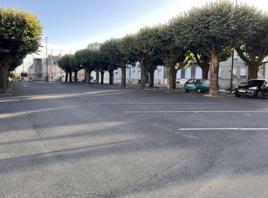 Emplacements de stationnement extérieurs ombragés sous les arbres avec marquage au sol.