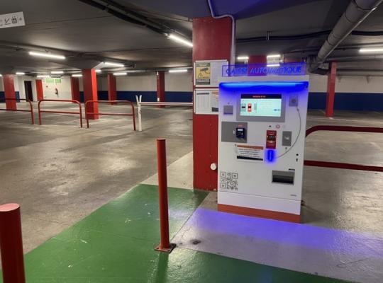 Caisse automatique de paiement du parking avec écran tactile et signalétique lumineuse bleue.