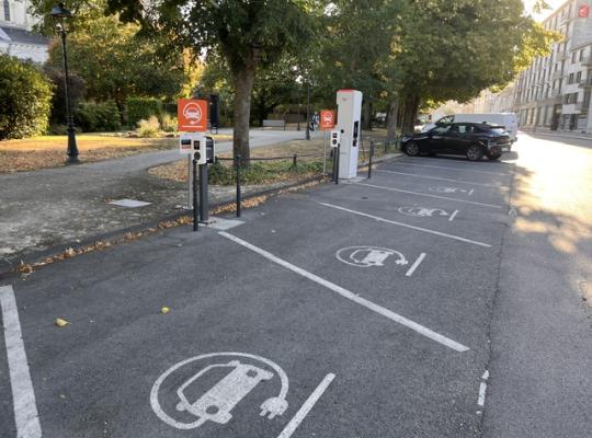 Places de stationnement réservées aux véhicules électriques avec bornes de recharge et marquage au sol.