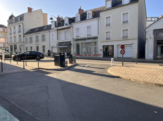Voie de sortie du parking sécurisée par une barrière levante et un panneau stop donnant sur la rue.