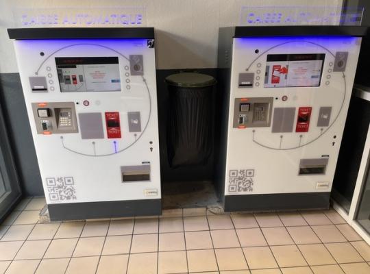 Deux caisses automatiques de paiement à écran tactile installées dans un espace couvert.