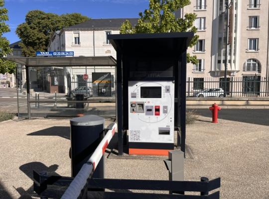 Caisse automatique de paiement installée sous un abri couvert près de la station de taxis.