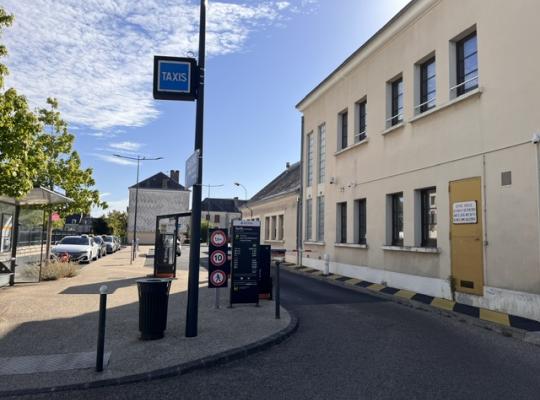 Voie d'accès au parking courte durée équipée d'un totem tarifaire, de barrières et d'une enseigne taxis.
