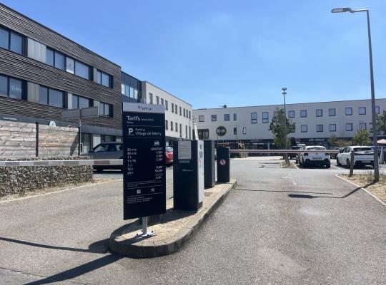 Entrée du parking du Village de Mercy avec panneau tarifaire EFFIA et barrière.