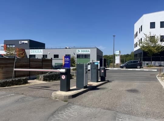 Voies d'accès du parking avec barrière automatique, bornes et enseigne DEKRA.