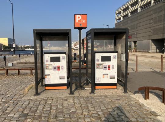 Deux caisses automatiques de paiement de stationnement abritées dans des cabines vitrées.