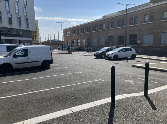 Places de stationnement à découvert avec marquage au sol et voie de circulation.