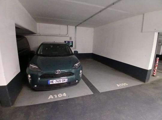 Voiture verte garée à la place A104 dans un parking souterrain.