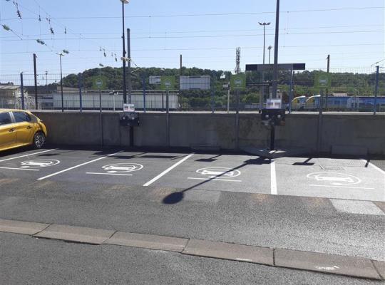 Places de stationnement réservées aux véhicules électriques avec bornes de recharge et marquage au sol.