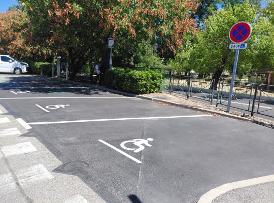 Emplacements de stationnement réservés aux personnes à mobilité réduite (PMR) sur le parking extérieur.