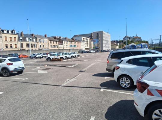 Parking extérieur découvert avec de nombreuses places de stationnement.