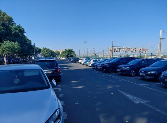 Vue d'ensemble des rangées de stationnement découvert à proximité des infrastructures ferroviaires.