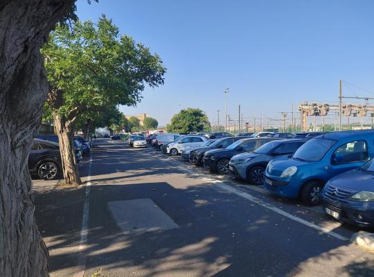 Emplacements de stationnement ombragés en extérieur, situés le long des voies ferrées.