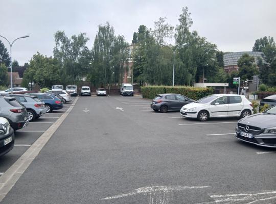 Aire de stationnement extérieure à ciel ouvert avec emplacements délimités pour véhicules.