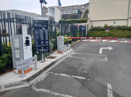 Borne de distribution de tickets, barrière automatique et panneau tarifaire à l'entrée du parking P2.