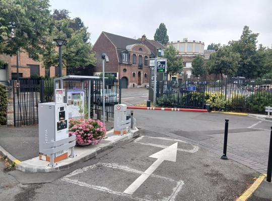 Borne de paiement en sortie, barrière automatique et marquage au sol vers la rue.
