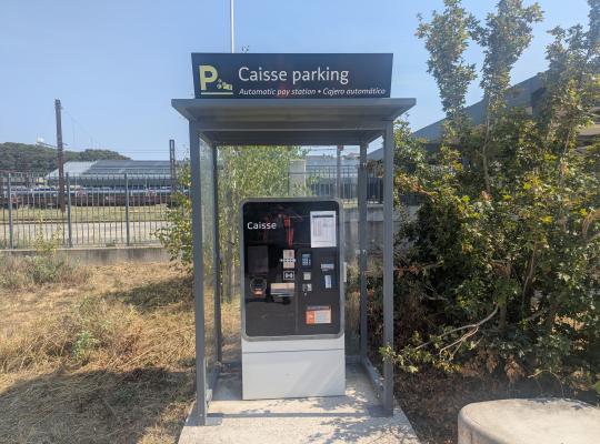 Caisse automatique de paiement en libre-service installée sous une cabine vitrée.