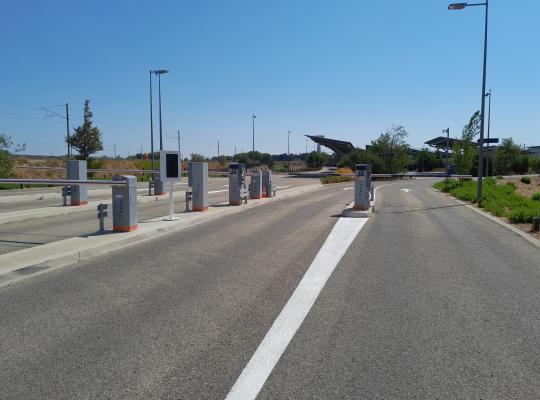 Voies d'accès au parking P2 équipées de bornes de contrôle et de barrières automatiques sous un ciel dégagé.