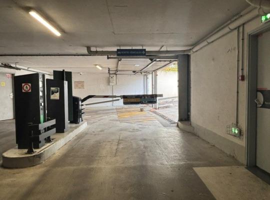 Voie de sortie intérieure du parking avec bornes de paiement et barrière.