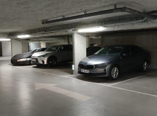 Rangée de voitures garées dans un parking souterrain éclairé.