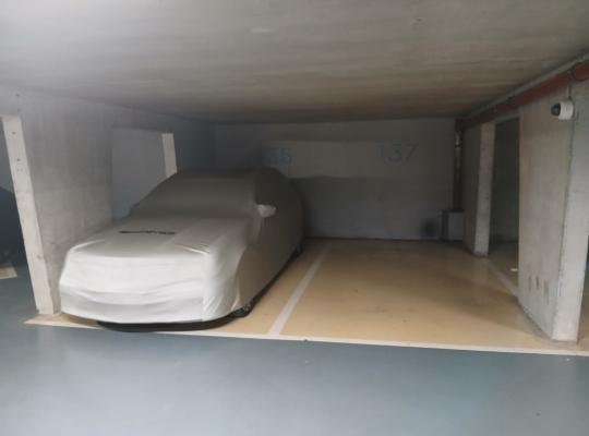 Voiture sous bâche blanche à la place 136 d'un parking souterrain.