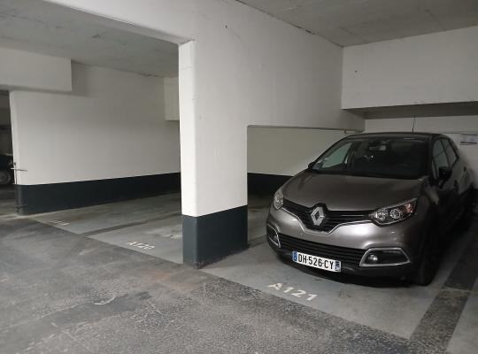 Voiture grise garée à la place A121 dans un parking souterrain.