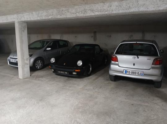 Voitures de différentes marques stationnées en bataille dans un parking couvert.