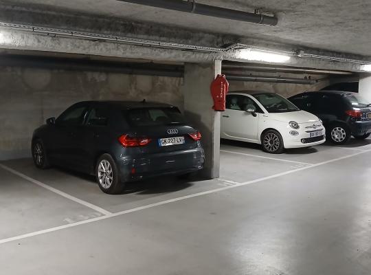 Voitures garées dans un parking souterrain éclairé, avec un extincteur.