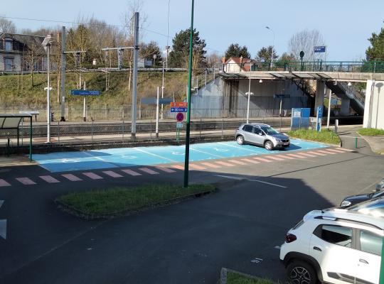 Emplacements réservés PMR peints en bleu et abri deux-roues au parking Parc Relais Gare de Longueville.