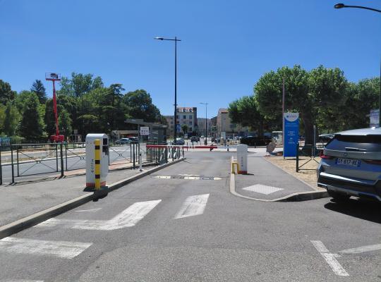 Bornes de contrôle et barrières automatiques régulant l'accès au parking.